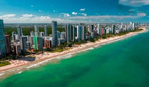 Vista aérea da orla da Praia de Boa Viagem em Recife durante o pôr do sol para planejamento do Réveillon 2027.